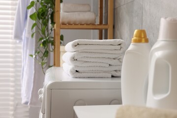 Obraz na płótnie Canvas Soft towels, detergents and washing machine indoors, closeup