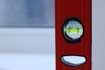 Red building level on white windowsill indoors, closeup. Space for text