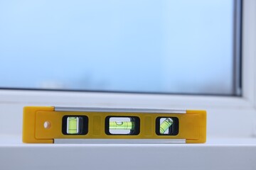 Yellow building level on white windowsill indoors, space for text
