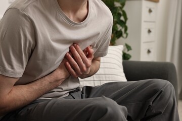Man suffering from heart hurt on sofa at home, closeup