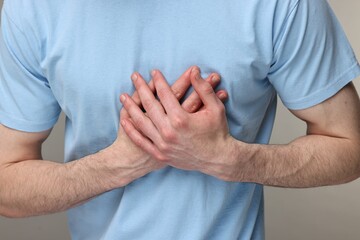 Man suffering from heart hurt on grey background, closeup
