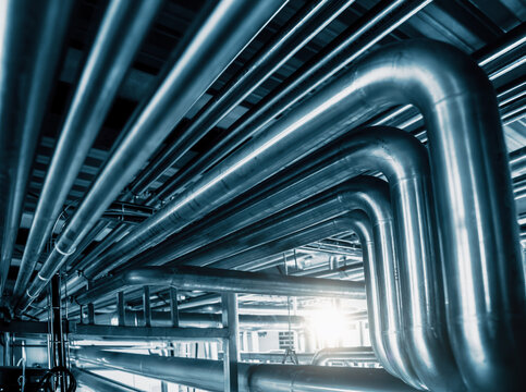 Network of gleaming steel pipes runs with precision, illustrating vital veins of industrial facility. Abstract pipe industry background