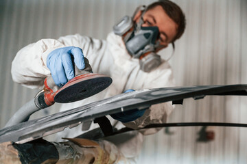 Polishing the surface. Repairman is working with carcass of the car in the garage