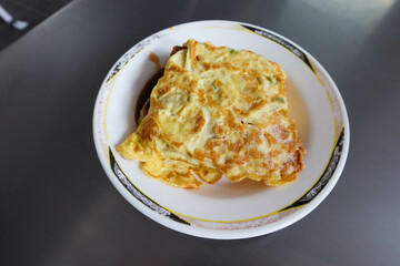 carrot pudding wrapped with fried egg omelette on a white plate on a iron metal table as Taiwanese breakfast