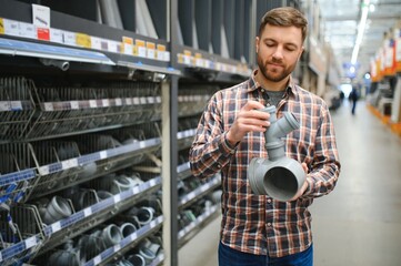 male plumber in a hardware store chooses the sewer pipes, the concept of plumbing work in the house