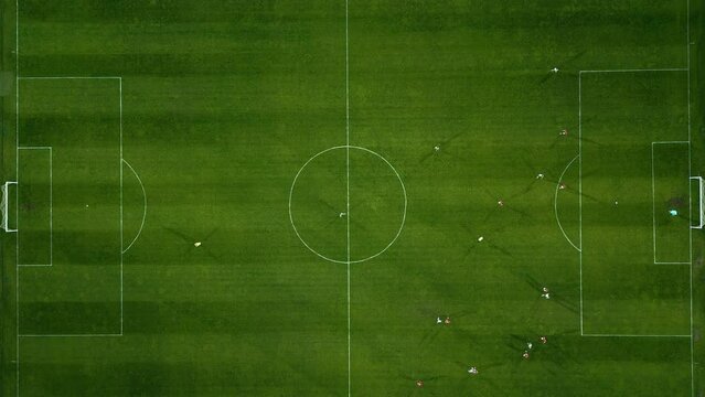 Aerial view of a soccer field in action, with players running, passing, and scoring goals.