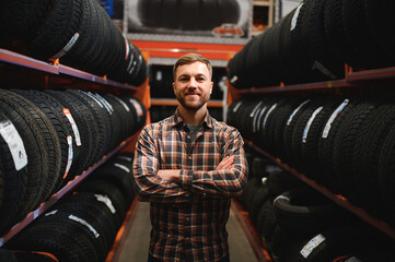 Glad male customer taking new tires in the supermarket for buying. He looks happy. Big shopping mall with car goods