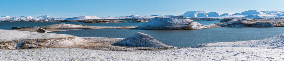 Snow covered landscape in panorama format with lake Myvatn and a number of small volcanic explosion...