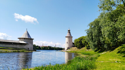 Ancient stone tower with wooden roof of Kremlin on embankment of cross Pskova and Velikaya river. Pskov, Russia. Old fortress. Blue sky. Tourist attractions. Traveling. Architecture. Fort. Landscape.