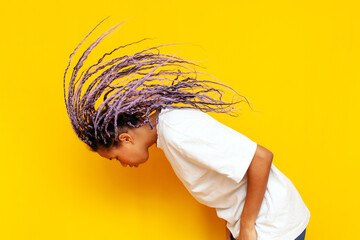 young african american woman with dreadlocks waving her head and dancing on yellow isolated...