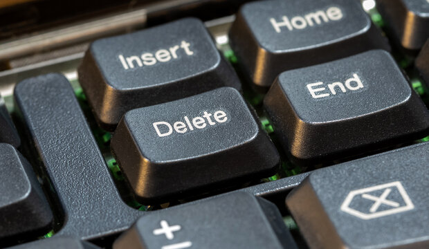 Focus on a delete key on a simple laptop computer keyboard, object macro detail, extreme closeup, nobody. Deleting files, removing content, digital data deletion simple abstract concept symbol - Powered by Adobe