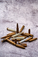 From above of collection of fired golden bullets and unfired cartridges with white plastic case arranged on rough floor at daytime