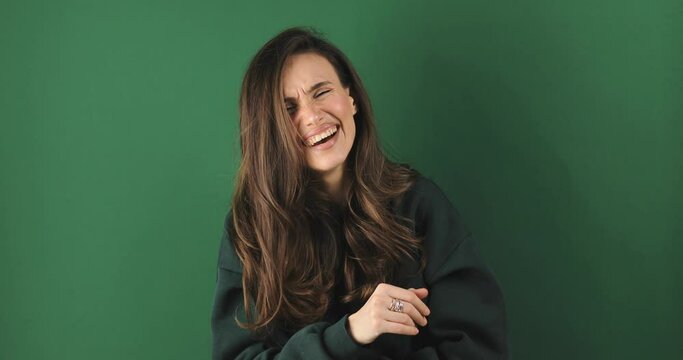 Young excited cheerful funny brunette woman look camera laugh smiling watch comedy movie, listening joke, pointing index finger on you isolated on green background studio portrait.