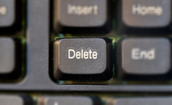Focus on a single Delete key on a laptop computer keyboard top down view from above, macro detail, extreme closeup, nobody. File deletion, deleting and removing digital data, removal abstract concept