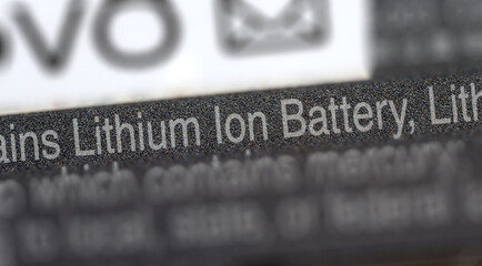 Contains Lithium Ion Battery label printed on a generic electronic device laptop tablet. Li-Ion batteries waste and environment, Lithium-Ion battery electronics simple concept symbol closeup, nobody