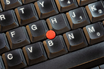 Red pointing stick on a laptop computer keyboard, macro detail extreme closeup shot from above,...