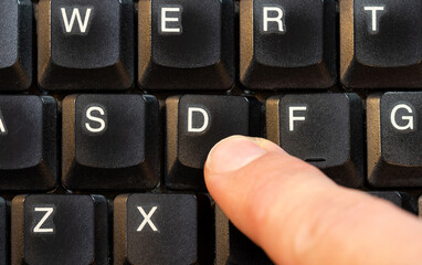 Man pressing a single D key on a modern laptop computer keyboard, finger pushing a key top view shot from above, one person. One single letter symbol input abstract concept, char, character value