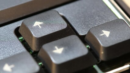 Man pressing the up arrow key on a simple laptop computer keyboard, macro, extreme closeup detail. Finger presses the forward arrow, moving forwards, progress simple abstract concept, one person