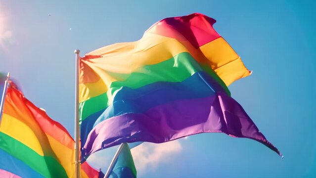 Rainbow flag fluttering in the breeze under blue sky. Clear day outdoor