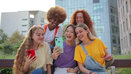 Goup of only women having fun using their cellphones. Females sitting outside and browsing on internet with a smartphone connection app. Girls watching the socialmedia with a mobile phone on a meeting