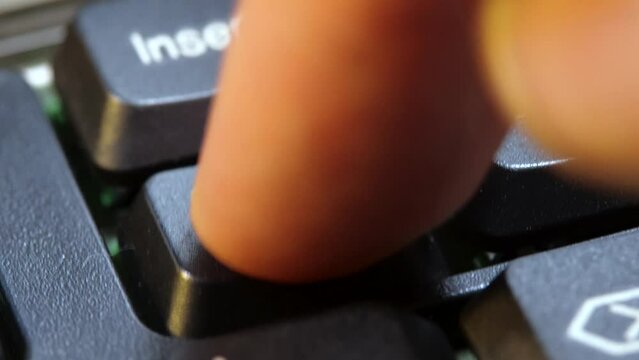 Finger pressing a delete key on a simple laptop computer keyboard, object macro detail, extreme closeup. Man deleting files, removing content, digital data deletion simple abstract concept symbol