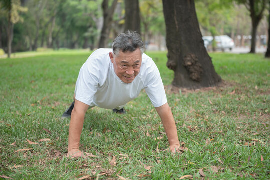 Elderly Asian man doing push-ups in an outdoor park Ideas for exercising in retirement - Powered by Adobe