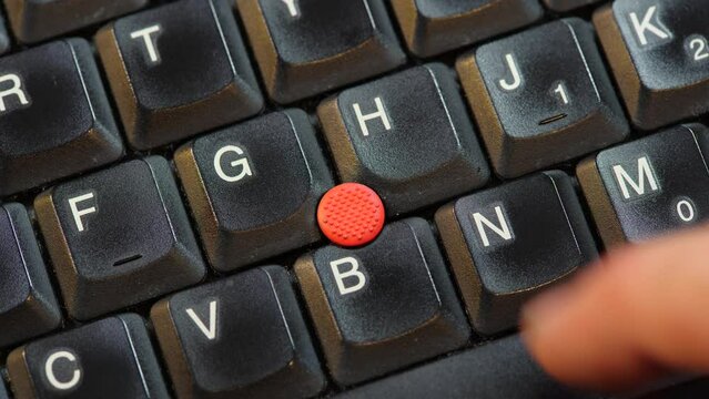 Removing the red pointing stick on a laptop computer keyboard, macro detail extreme closeup shot from above, nobody, no people. Mouse input emulation on notebooks laptops concept. Mouse track point