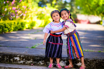 The sisters hug each other with a lot of love and joy. Pair of Mayan sisters in a park in the Latin...