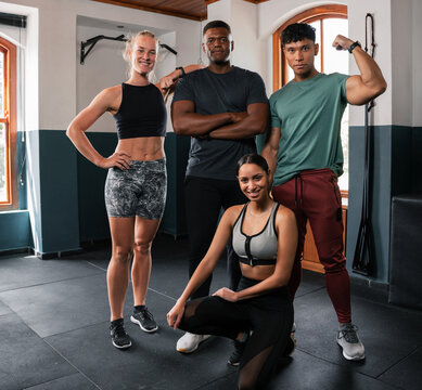 A group of people posing with arms around shoulders in a gym for a photo
