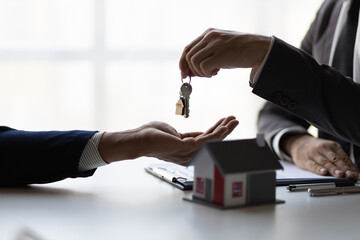 Real estate agent holding house keys is handing them over to a client after signing a home purchase...