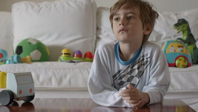 Young boy in striped pajamas contemplating in his toy-filled bedroom