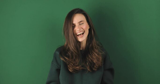 Amazed excited woman win in lottery in pink long sleeves top open mouth in surprise looking at camera with big eyes, shocked isolated on green background. Oh my god wow, yes gesture, win symbol.