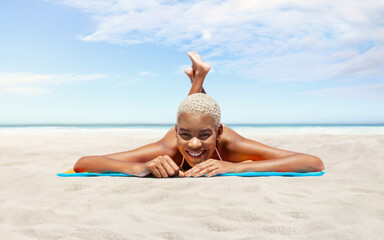 Happy young woman lying on sand beach, on a sunny day by the seaside, concept of a summer beach holiday, booking travel and resort accommodations, panoramic with a sky and sea horizon for copy space