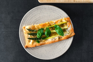 Spargelpizza zu Hause selber machen mit grünem Spargel auf hellem Teller in Stück geschnitten 