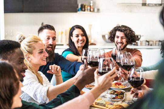 Joyful toast at diverse dinner gathering - cheerful friends share a moment of happiness with wine, symbolizing unity and joy in diversity.