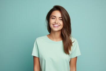 Fototapeta premium A woman with long brown hair is smiling and wearing a green shirt