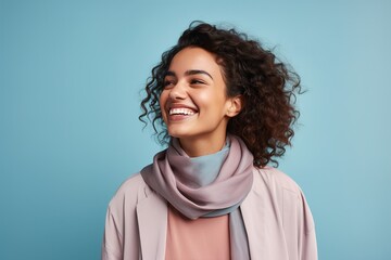 A woman with curly hair is smiling and wearing a scarf