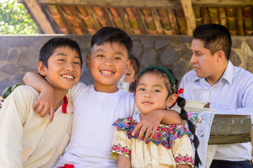 The older brother, sitting in the center of the group, hugs his brothers with love and joy and everyone smiles for a portrait photo.