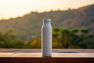 White plastic bottle mockup. Mock up rests on a wooden table with a mountain backdrop. Blank reusable flask overlooking a breathtaking lakeside vista