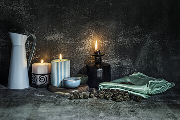 A still life with a green satin cloth next to several lit candles