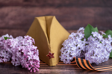 May 9, Victory Day holiday. Military cap, St. George's ribbon and bouquet of sirens on a wooden...