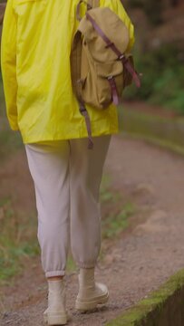 A girl in a yellow jacket travels with a backpack and visits extraordinary places and trails on the island of Madeira, Levada dos Tornos, Portugal. Vertical video