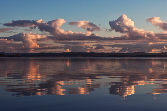 Sunset colored stormy clouds mirrored in the still water of a lake in western Oregon