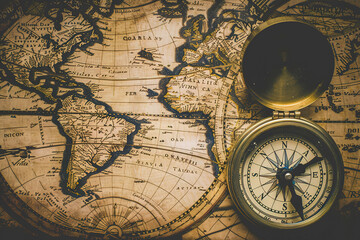 Fototapeta na wymiar A vintage map of the world with an old-fashioned compass placed on top