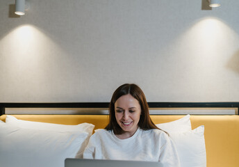 Happy Woman Using Laptop in Comfortable Bedroom. Copy space for text.