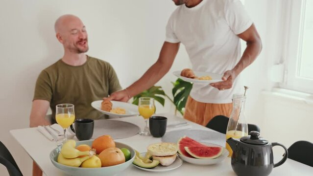 Affectionate moment as a man serves breakfast to his partner, depicting love and care in a cozy home setting.