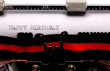 typewriter with black ink Happy Birthday text on white paper