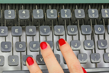 polished nails of Female secretary typing on the keys of an old typewriter