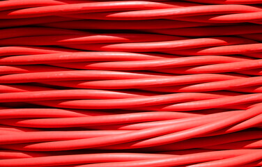 background of detailed red electrical cable used for high voltage power transmission from a power...