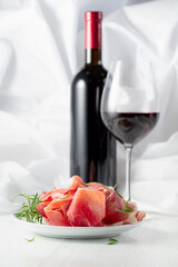 Prosciutto with rosemary and  red wine on a white wooden table.